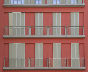 full frame shot of the red facade of a residential building with balconies - Powered by Adobe