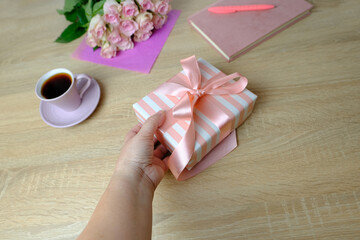 bouquet of white, pink roses, cup of tea, coffee, gift with satin ribbon, flowers for professional holiday on light table in office, concept of mother's, Valentine's day, birthday, selective focus
