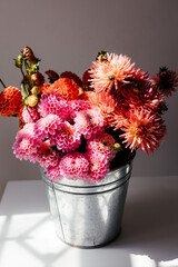 photo of a bouquet created from wild fresh spring flowers photographed on a white background in daylight, a metal bucket with flowers