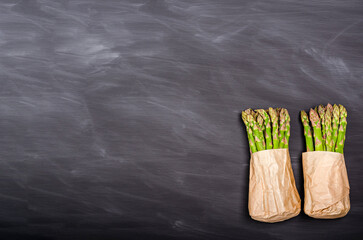 Green asparagus in a paper bag on a black background with place for text.