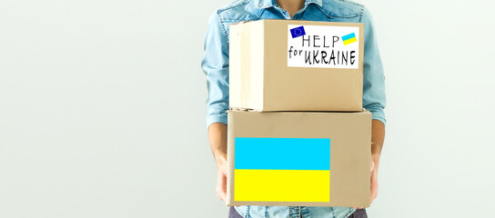 A man holds a box of aid for Ukrainian refugees and poor citizens who find themselves in a war between Ukraine and Russia. Humanitarian aid concept. Donate for refugees.