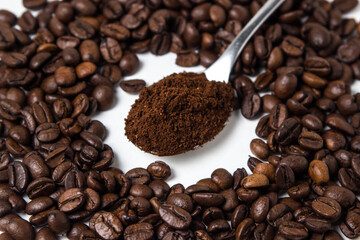 A spoon of ground coffee next to coffee beans on a white background. Roasted coffee beans. tonic drink