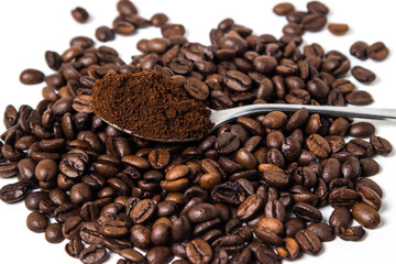 A spoon of ground coffee next to coffee beans on a white background. Roasted coffee beans. tonic...