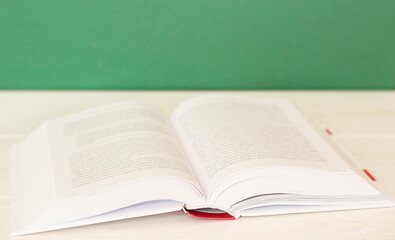 an open white book lies on a white wooden table against a green wall