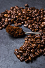 A spoon of ground coffee next to coffee beans on a black background. Roasted coffee beans. tonic drink