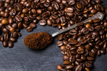 A spoon of ground coffee next to coffee beans on a black background. Roasted coffee beans. tonic...