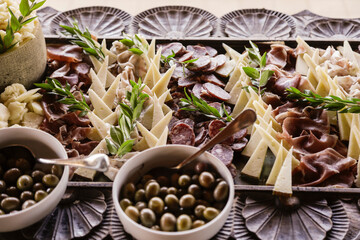 Antipasti misti di olive , formaggi e salumi ben presentati su tavola imbandita 