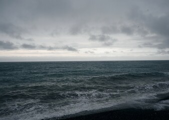 Dark natural background of inclement weather on the sea. Black sea and gray sky. Rain and waves.