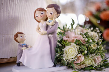 cake topper posizionati sopra la torta di nozze raffiguranti gli sposi in miniatura e il figlio...