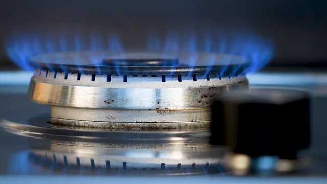 Br&ucirc;leur d'une cuisini&egrave;re &agrave; gaz qu'une main vient allumer puis &eacute;teindre en tournant un bouton