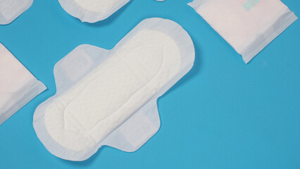 Woman sanitary napkins on blue background. Top view. Absorbent pads worn by women to absorb menstrual blood. Comfortable white sanitary napkins arranged on light blue paper. Represent Hygiene concept