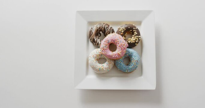 Video of donuts with icing on white plate over white background