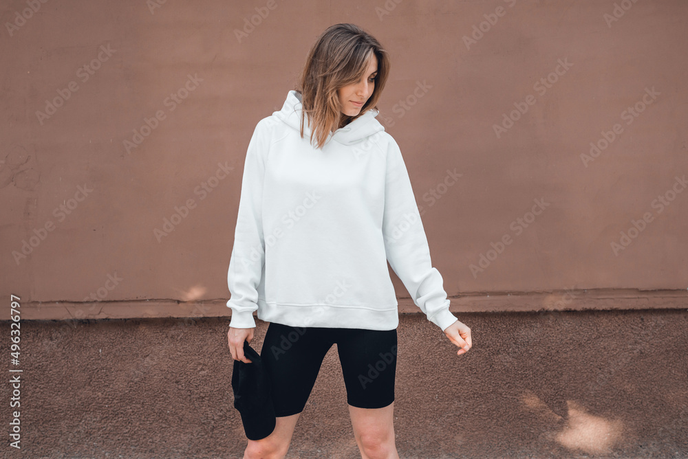 Poster Attractive woman in white hoodie standing on the street , mockup