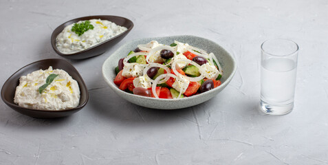 Traditional drink Ouzo or Raki and traditional greek salad, tzatziki and olives