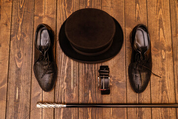 dettaglio di cappello , bastone scarpe e  cinta eleganti su tavolo in legno 