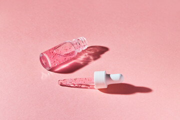 Nail and cuticle serum scrub in a transparent glass bottle on a pink background. Beauty and health care concept