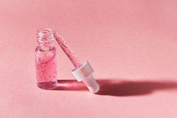 Nail and cuticle serum scrub in a transparent glass bottle on a pink background. Beauty and health care concept