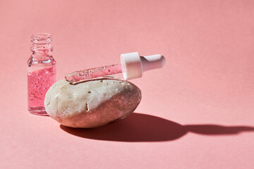 Nail and cuticle serum scrub in a transparent glass bottle on a pink background. Beauty and health care concept