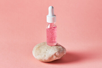 Nail and cuticle serum scrub in a transparent glass bottle on a pink background. Beauty and health care concept
