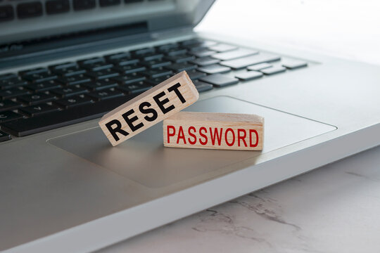 Reset password text on wooden block cube placed on laptop or notebook.