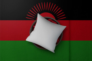 Patriotic pillow mock up on background in colors of national flag. Malawi