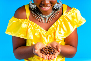 beautiful africa-american woman with yellow turban ower the head showing fresh coffee beand in...