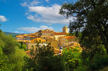 Fototapeta na wymiar Scenic view on hill with picturesque medieval mediterranean village with church, blue sky, fluffy clouds - Ramatuelle, France