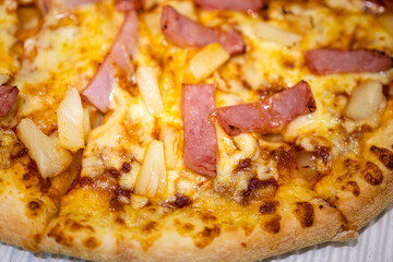 Hawaiian pizza with sliced ham and pineapple topping. Italian food top view close-up photo.