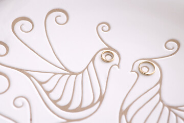 fedi d'oro che vanno a formare gli occhi di incisione di due uccelli su un piatto 