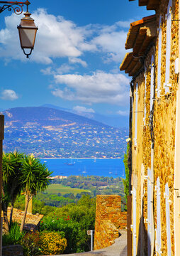View beyond ancient mediterranean natural stone house wall, street lamp from hill top village Gassin on blue sea bay of gulf of St. Tropez.
