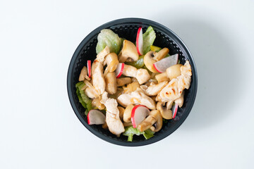 Vegetable salad with chicken in a disposable bowl.