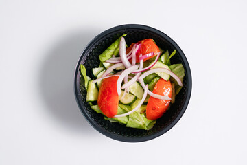 Vegetable salad with tomatoes in a disposable bowl.