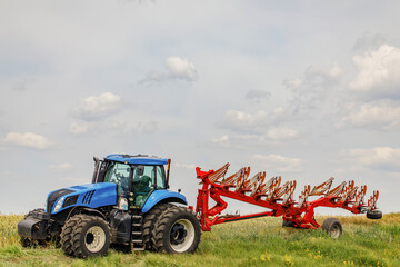 Obraz premium Farmer in tractor at industrial crop farm field spraying green wheat field with herbicides pesticides and fungicides 
