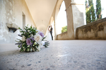 bouquet di fiori in primo piano e sposi in lontananza sfocati che camminano