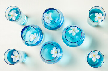 Flores de cerezo flotando en copas azules, ambiente primaveral y fresco de decoración