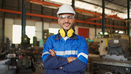 Fototapeta na wymiar Close up portrait of confident engineer man wearing safety helmet and glasses standing in the CNC manufacturing factory. Looking forward and crossed arm. Technology and industrial concept