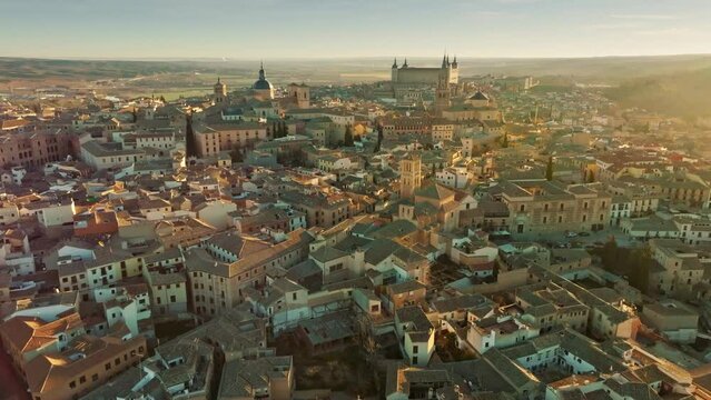 Flight over houses and cathedral in Toledo at sunset. Aerial view of Toledo, Castilla-La Mancha, Spain