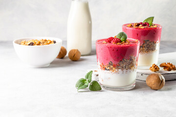Yogurt, raspberry smoothie and homemade granola in a transparent glass. Healthy breakfast or snack. Copy space
