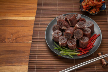 Blood sausage or Sundae in black plate on wooden table background.