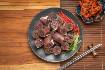 Blood sausage or Sundae in black plate on wooden table background.
