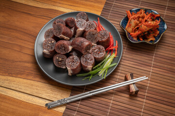 Blood sausage or Sundae in black plate on wooden table background.