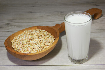 Large wooden spoon with oatmeal and a glass of milk