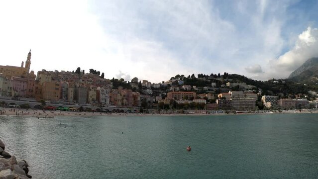 Menton, France, October 2, 2021: PAN SHOT SLOW MOTION - The Sablettes beach in Menton is located between the two ports (the Old Port and Garavan), along the Quai Bonaparte and the old town.