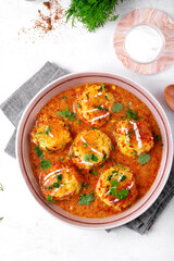 Malai Kofta served with yogurt and fresh herbs. Hot meal with potato and paneer cheese balls in tomato sauce. Indian cuisine. Top view