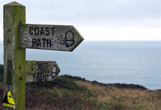 Signpost showing direction for coast path with sea in background