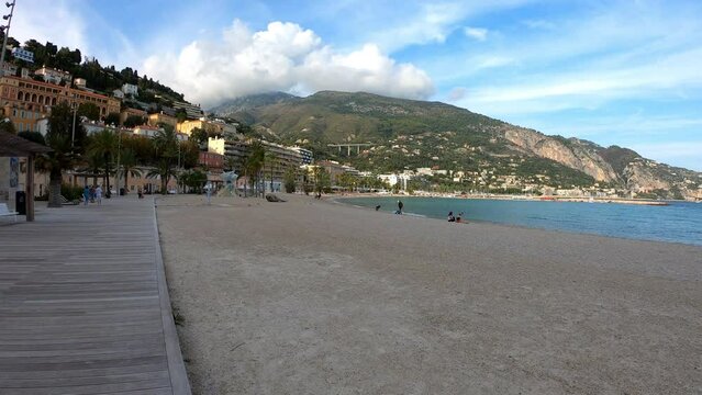 Menton, France, October 2, 2021: DOLLY SHOT SLOW MOTION  - The Sablettes beach in Menton is located between the two ports (the Old Port and Garavan), along the Quai Bonaparte and the old town.