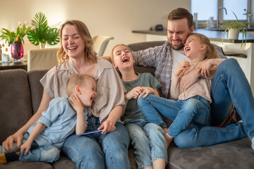 family portrait. family photo in which mom, dad, daughters, son and dog are smiling and hugging on the couch in a cozy homely atmosphere