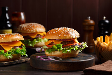Trois Burgers classiques fait maison sur une planche rustique avec des frites et ketchup