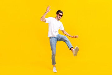 Full body photo of cool young brunet guy dance wear eyewear t-shirt jeans footwear isolated on yellow background
