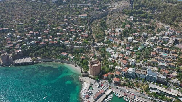 Top view at Alanya Kalesi (Castle). View of Alanya harbor from Alanya peninsula. Kizil Kule - main tourist attraction in Alanya. Landscape with marina and Red tower in Alanya peninsula
